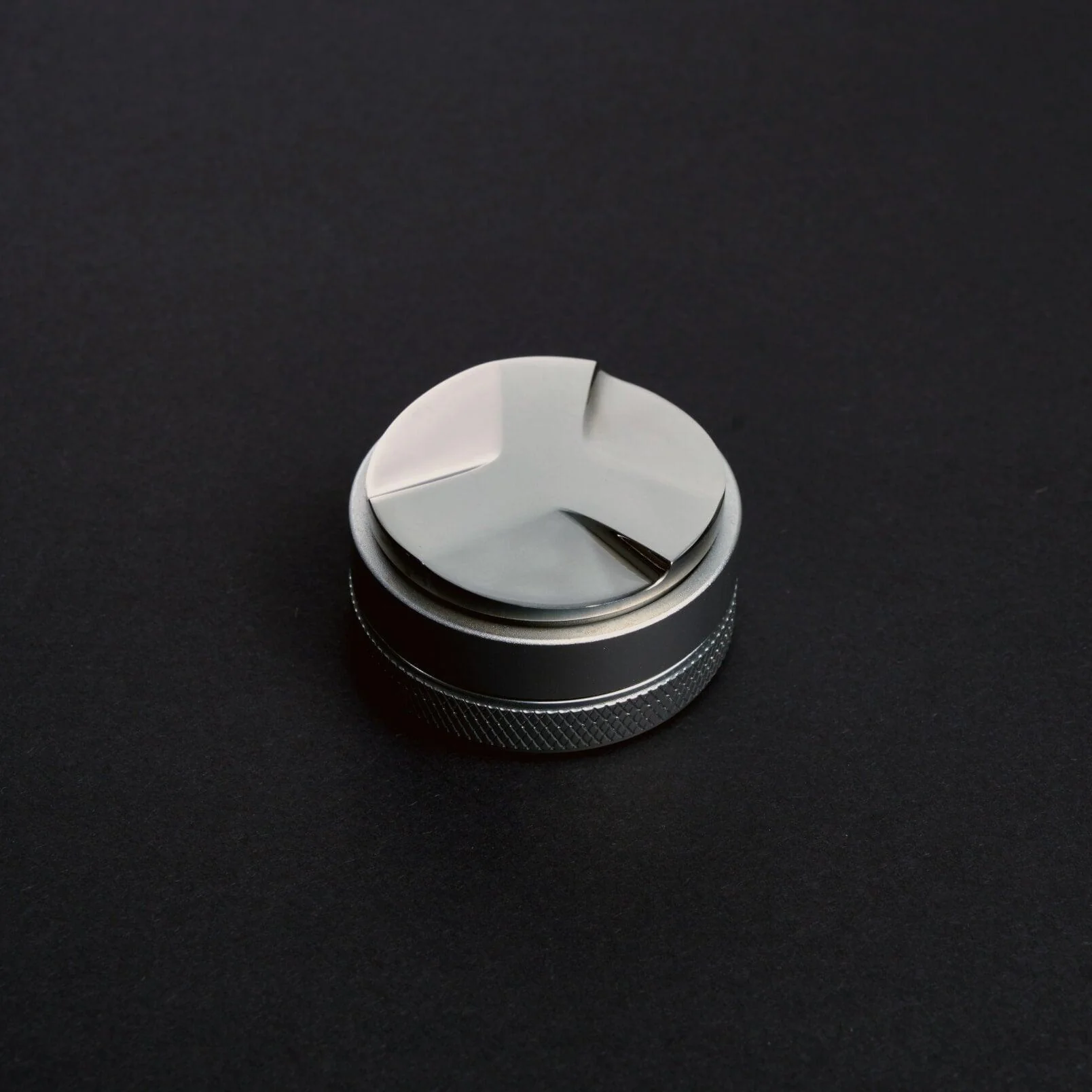 Coffee distributor tool on a dark background.